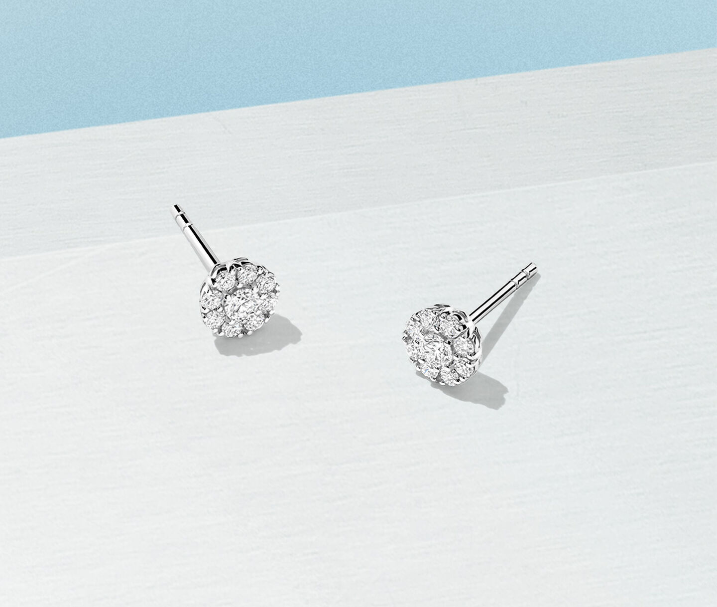 Birks Snowflake diamond cluster earrings on a light blue background.